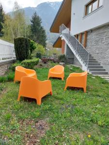 vier orangefarbene Stühle im Gras vor einem Gebäude in der Unterkunft Villa Rostagno in Entracque