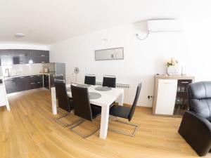 a dining room with a white table and black chairs at Apartmani Jastreb 2 in Jastrebarsko