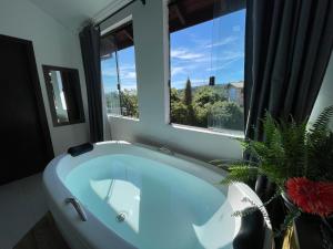 bañera blanca grande en el baño con ventana en Pousada Solar dos Lírios - Praia do Rosa en Praia do Rosa