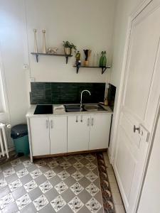 een keuken met witte kasten, een wastafel en een deur bij Le Sauvage - 7 personnes - Gare - BCLA in Le Mans