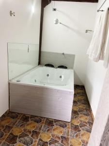 y baño con bañera y suelo de baldosa. en Hostal Inn II Rionegro, en Rionegro