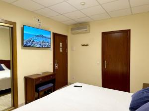 a hotel room with a bed and a tv on the wall at Hotel Sancho in Hospitalet de l'Infant
