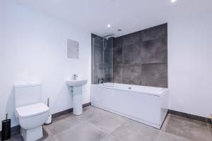 a bathroom with a toilet and a tub and a sink at Silver Street by Staycay in Bury