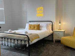 a bedroom with a bed with a sign that says lets stay home at Spacious Victorian Birkdale Apartment with Garden in Southport