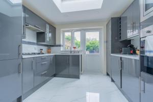 a large kitchen with gray cabinets and a window at Hayes Home - Easy links to LHR and London in Northolt