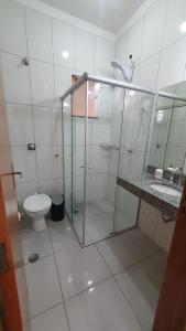 La salle de bains est pourvue d'une douche en verre et de toilettes. dans l'établissement Casa no centro com 4 quartos e ar condicionado, à São João Batista do Glória