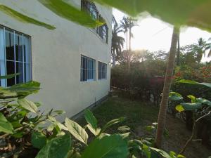 a white building with a palm tree in front of it at Casa Ixtlán Planta Baja in Santa Cruz Huatulco