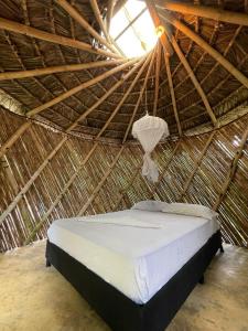 a bed in a straw hut with a light at Casa Alma in Capurganá