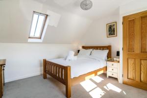 1 dormitorio con 1 cama con sábanas blancas y ventana en The Loft, en Mickleton