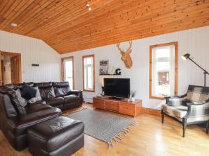 a living room with leather furniture and a flat screen tv at Chalet C in Dornoch