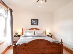 a bedroom with a wooden bed with white walls at Chalet C in Dornoch