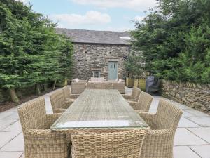einen langen Tisch mit Stühlen und ein Steingebäude in der Unterkunft Yew Cottage in Backbarrow