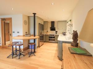 eine Küche mit einer Theke, einem Tisch und Stühlen in der Unterkunft Yew Cottage in Backbarrow