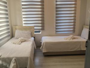 two beds in a room with white sheets and windows at Taksim Cihangir otel in Istanbul