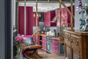 a kitchen with pink cabinets and a chair in it at The Blue Anchor House - close to London in Hertford