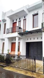 a white house with a fence in front of it at Ganendra Syari'ah Guesthouse in Dieng