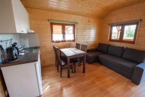 eine Küche und ein Wohnzimmer mit einem Tisch und einem Sofa in der Unterkunft Lazur Apartamenty Domki in Sarbinowo