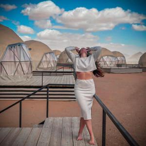 a woman in a dress standing on a boardwalk at Rum Mars luxury camp in Wadi Rum