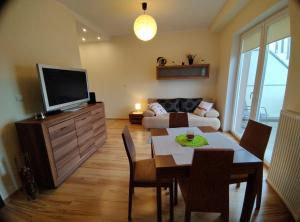 een woonkamer met een televisie en een tafel met stoelen bij Apartament Gardena II Olsztyn Jaroty in Olsztyn