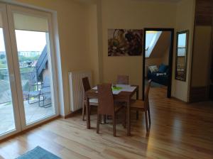 a dining room with a table and chairs and a balcony at Apartament Gardena II Olsztyn Jaroty in Olsztyn