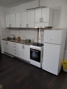 una cucina con armadietti bianchi, piano cottura e frigorifero di Titan 