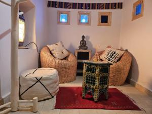 sala de estar con 2 sillas de mimbre y mesa en Kasbah La Cigogne, en Aït Ben Haddou