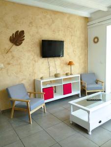 a living room with two chairs and a tv on the wall at Villa Tahitienne in Frontignan