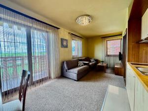 a living room with a couch and a large window at Tatragolf Resort Apartment I206 Tatranská Lomnica in Veľká Lomnica