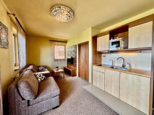 a living room with a couch and a kitchen at Tatragolf Resort Apartment I206 Tatranská Lomnica in Veľká Lomnica