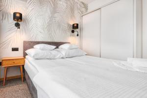 Un dormitorio con una cama con sábanas blancas y una mesa. en Kojak, en Jastrzębia Góra