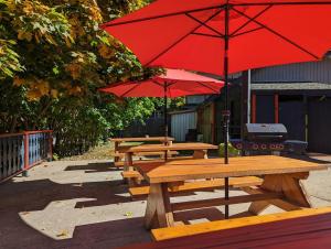 um grupo de mesas de piquenique com guarda-chuvas vermelhos em Alpine Inn & Suites em Nelson
