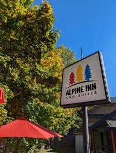 un panneau pour une auberge et des suites à côté d'un parapluie dans l'établissement Alpine Inn & Suites, à Nelson