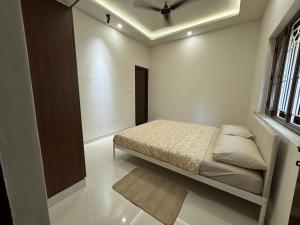 a bedroom with a bed and a window at Maple Grove Traditional Homes. in Bangalore