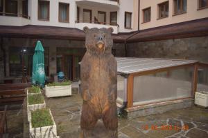 duży drewniany posąg niedźwiedzia przed budynkiem w obiekcie Villa Park Guest Apartments w Borowcu