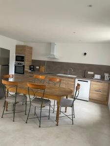 a kitchen with a wooden table and chairs at Maison de campagne "Le GAULT" in Baugé
