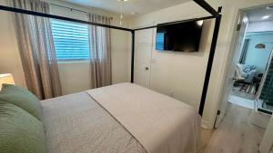 Schlafzimmer mit einem Bett, einem TV und einem Fenster in der Unterkunft Turtle Nest 8 - Quick Walk to Beach in Fort Myers Beach