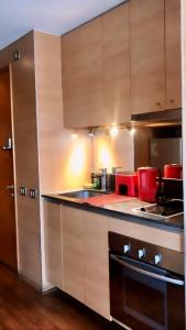 a kitchen with wooden cabinets and a stove top oven at Providencia Studio Suite con Terraza in Santiago