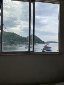 a window view of a body of water with boats at Farol do cais in Niterói