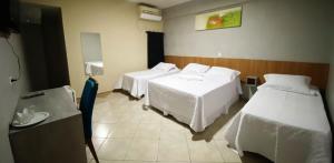 a hotel room with two beds and a table at Itaipu Hotel Foz do Iguaçu in Foz do Iguaçu