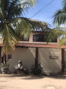 a dog sitting outside of a house with a palm tree at Pendotiba Hostel in São Gonçalo