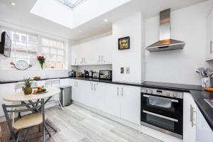 a kitchen with white cabinets and a small table at Trendy Rooms Spitalfields in London