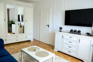 een witte woonkamer met een tv en een blauwe bank bij Clover Apartament in Cluj-Napoca