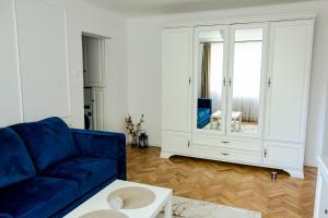 een woonkamer met een blauwe bank en een spiegel bij Clover Apartament in Cluj-Napoca