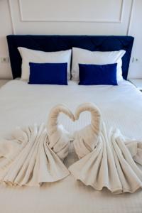 twee zwanen die een hart maken op een bed bij Clover Apartament in Cluj-Napoca