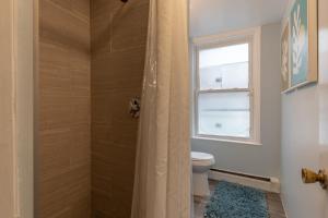 a bathroom with a shower with a toilet and a window at Central 3 Bed 1 Bath in Historic Building in Boston