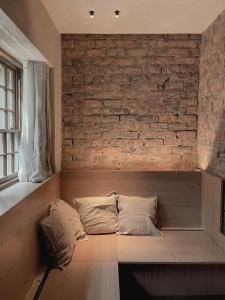 a bed with two pillows on it in a room with a brick wall at Loggia Studio in Edinburgh
