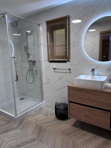 a bathroom with a shower and a sink and a mirror at Forest Hill domki - Międzyzdroje -KLIMATYZACJA in Międzyzdroje