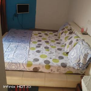ein Bett in einem Schlafzimmer mit einer Bettdecke und Kissen in der Unterkunft Belle vue in Douala