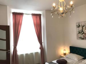 a bedroom with a bed and a chandelier and a window at The Bridge of Lies Apartment in Sibiu