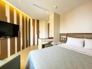 pokój hotelowy z łóżkiem i telewizorem z płaskim ekranem w obiekcie Ai Lai Fashion Hotel w mieście Taizhong